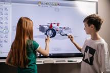 A boy and girl collaborate on a robotics project using a digital screen in a classroom setting. (Foto: Alena Darmel / Pexels)