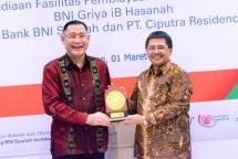 Direktur Utama BNI Syariah, Abdullah Firman Wibowo (kiri) menyerahkan cinderamata kepada Direktur PT Ciputra Residence, Mary Octo Sihombing (kanan).