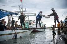 Pegawai BRI membantu nelayan