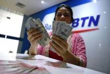 Petugas menghitung uang dolar Amerika Serikat di gerai penukaran mata uang Bank BTN/ FOTO: ANTARA FOTO/REPUBLIKA
