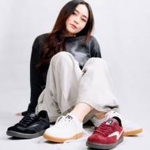 Seorang anak muda percaya diri memamerkan beberapa model sepatu Raingel Footwear.